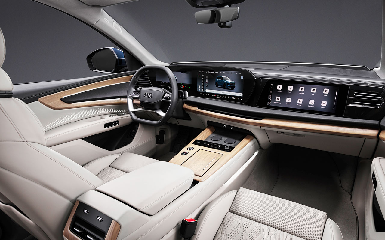 Interior do Audi Q7 com volante, painel digital e telas da central multimídia e do passageiro