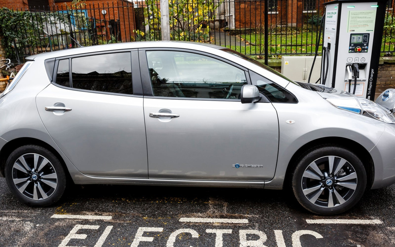 Nissan Leaf elétrico estacionado junto a carregador no Reino Unido