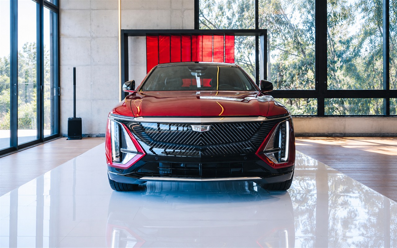 Cadillac Lyriq vermelho visto de frente, com faróis verticais e emblema da marca na grade