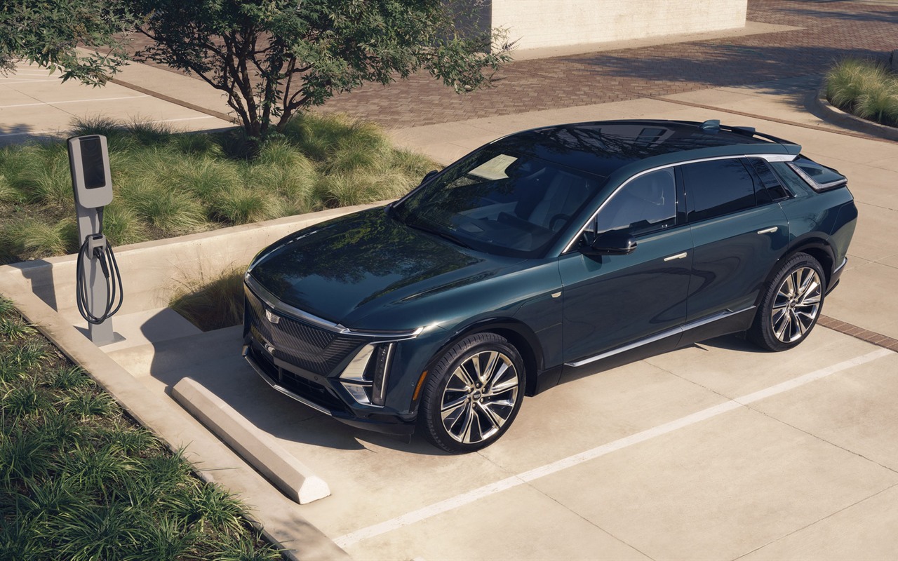Cadillac Lyriq Luxury ao lado de um carregador, visto de cima em ângulo dianteiro
