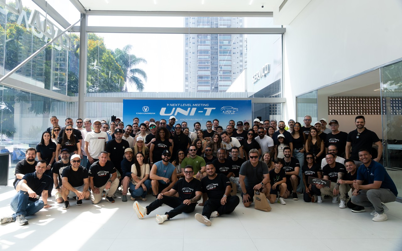 Participantes reunidos diante do painel do encontro do UNI-T Club BR na concessionária CAOA Changan