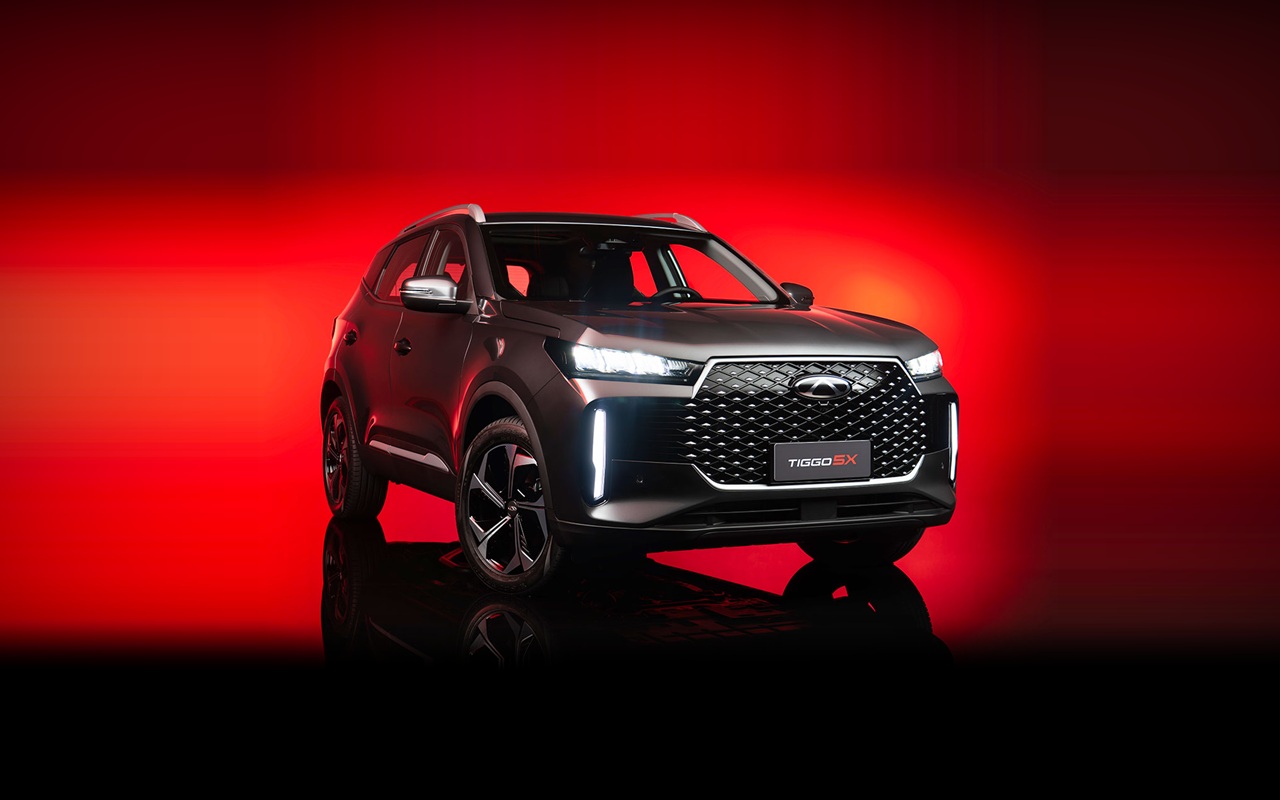CAOA Chery Tiggo 5X em vista dianteira de três quartos, inteiro e centralizado sobre fundo vermelho