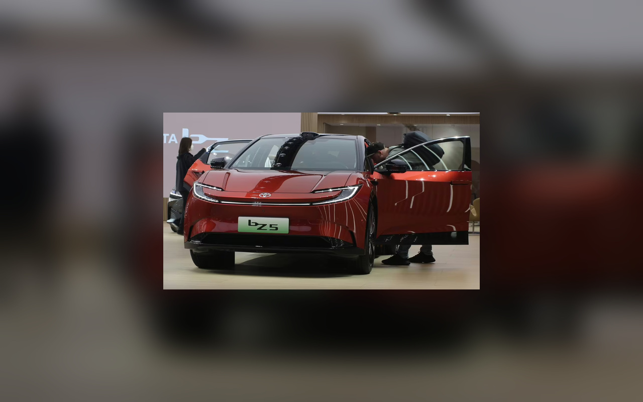 Toyota bZ5 vermelho em exposição na China, visto de frente com as portas abertas