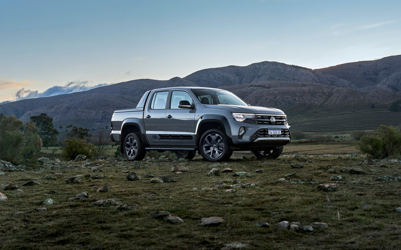 Volkswagen Amarok V6 Unlimited Cinza Moonstone vista de frente e de lado em paisagem montanhosa