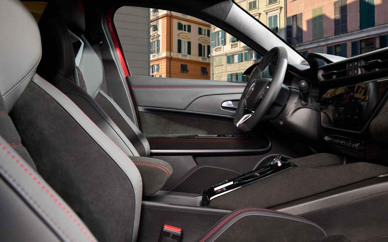 Bancos dianteiros, painel de porta e console do Alfa Romeo Junior MY27, com revestimento escuro e costuras vermelhas