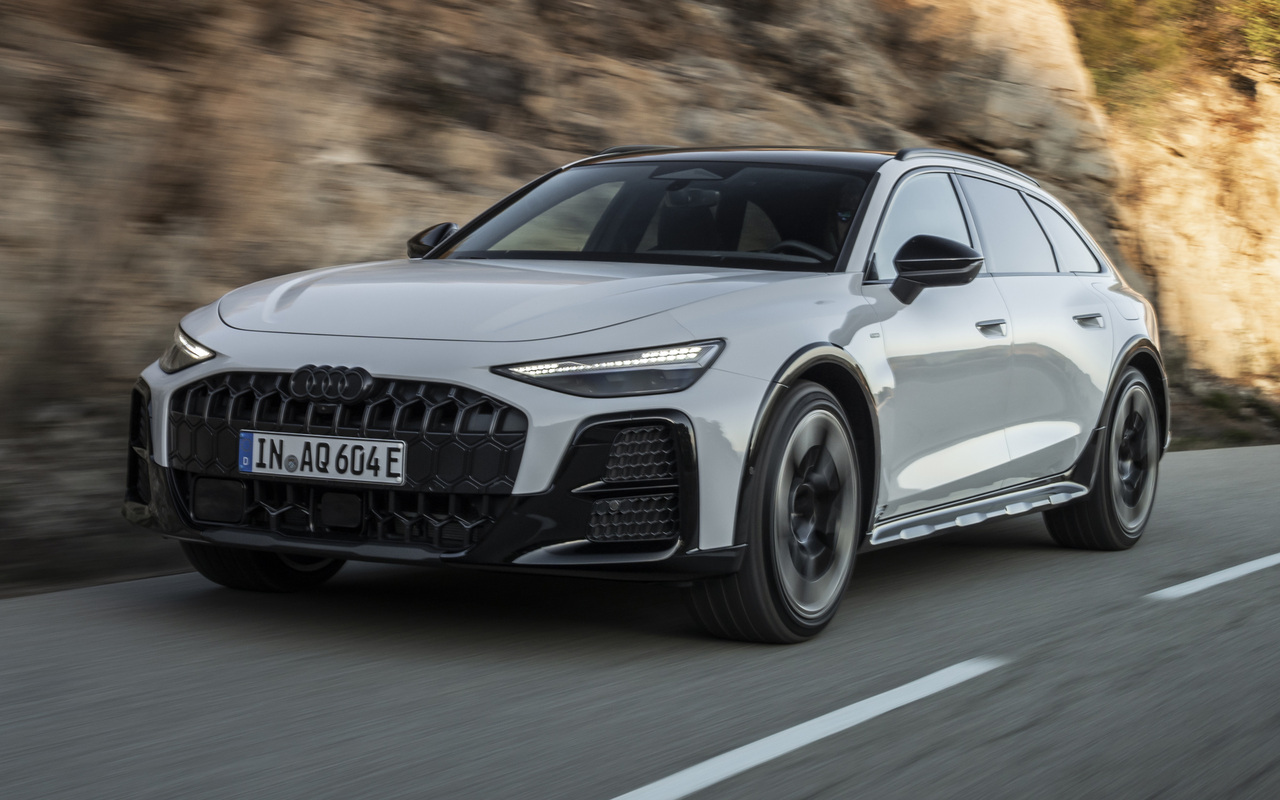 Audi A6 allroad e-hybrid branca vista de frente e de lado em uma estrada entre rochas