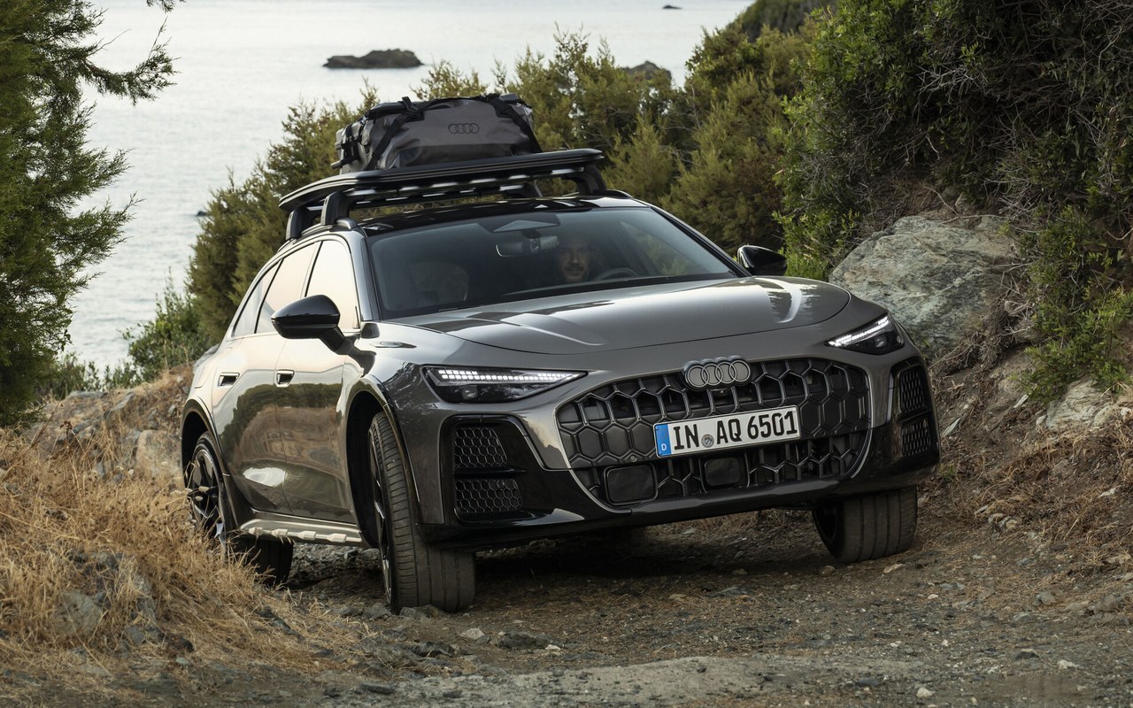 Audi A6 allroad TDI cinza vista de frente e de lado em um caminho de terra, com bagageiro no teto