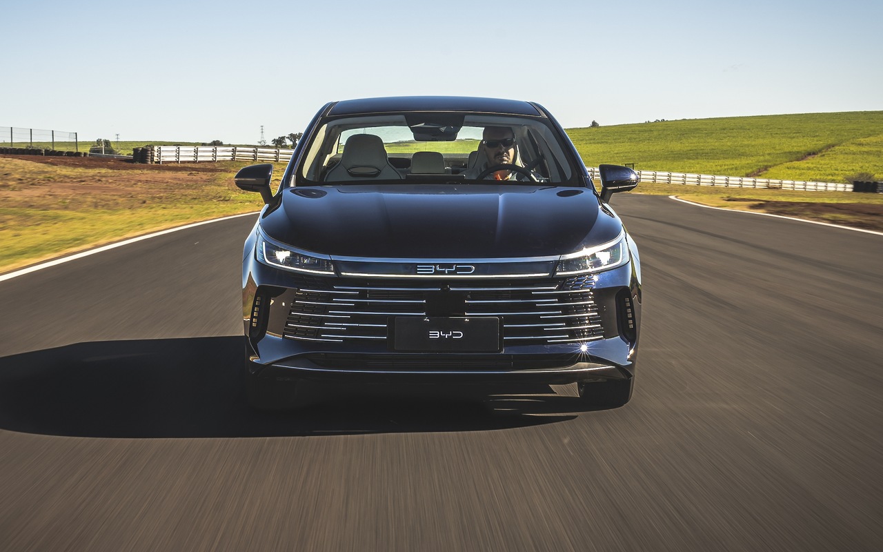 BYD King preto fotografado de frente em uma pista, com faróis e retrovisores visíveis