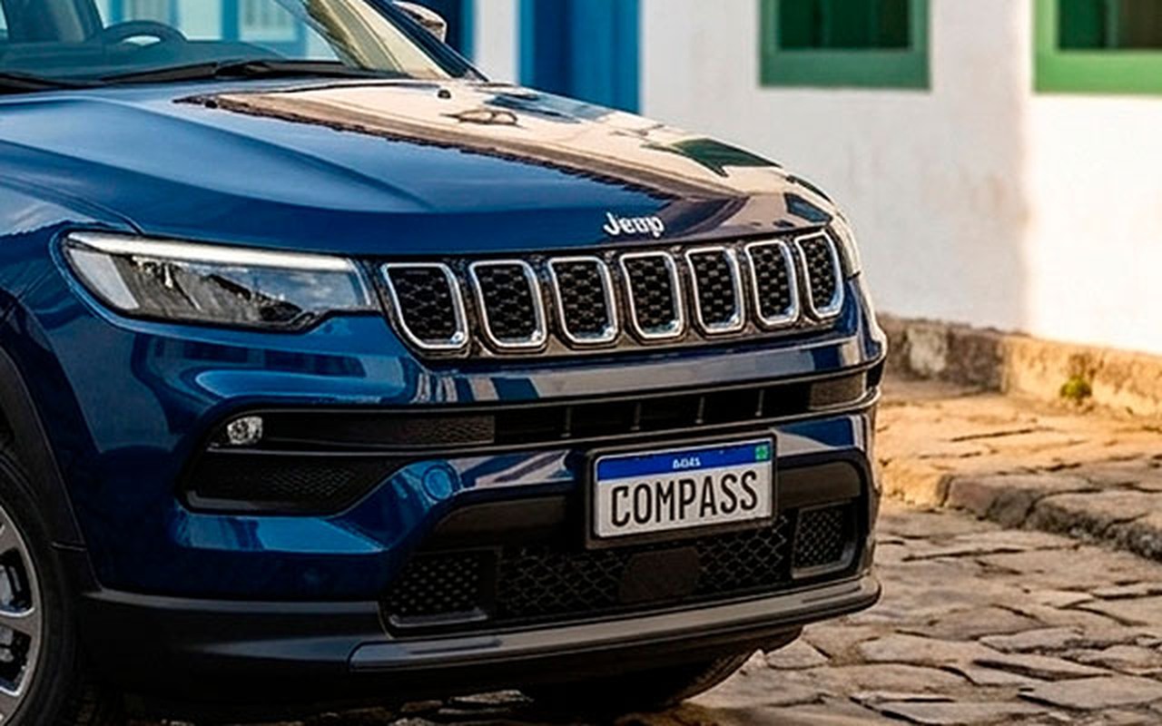 Detalhe frontal do Jeep Compass Sport azul, com grade de sete aberturas, emblema Jeep e identificação Compass