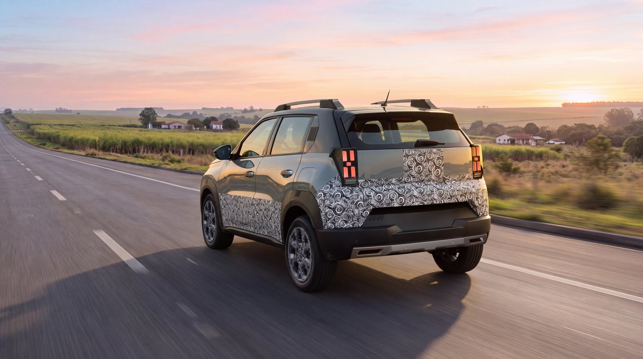 Protótipo do Fiat Argo X com camuflagem parcial visto de traseira e de lado em rodovia ao pôr do sol