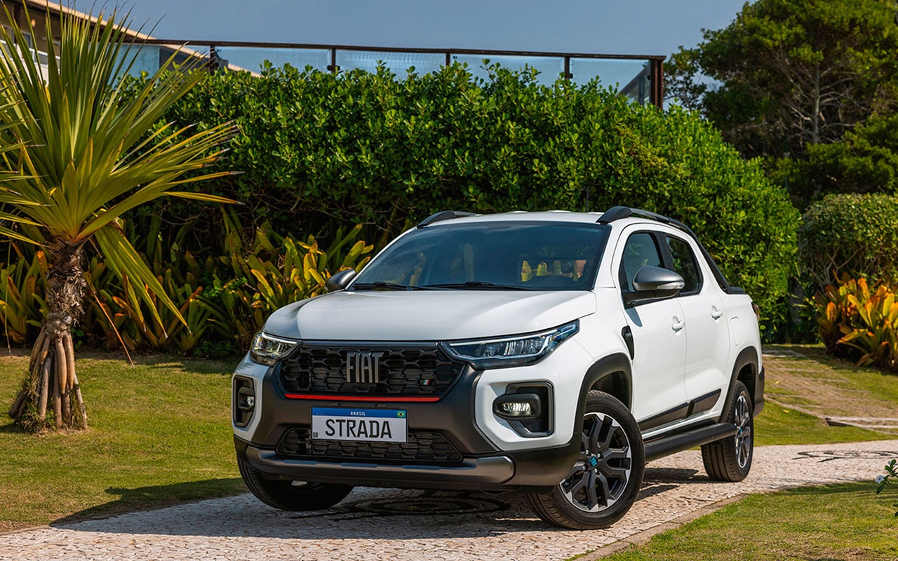 Fiat Strada Ultra branca vista de três quartos dianteiros em área ajardinada