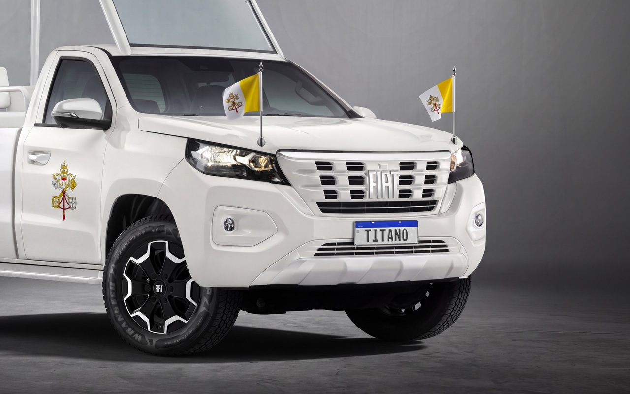 Dianteira da Fiat Titano branca adaptada como papamóvel, com bandeiras do Vaticano