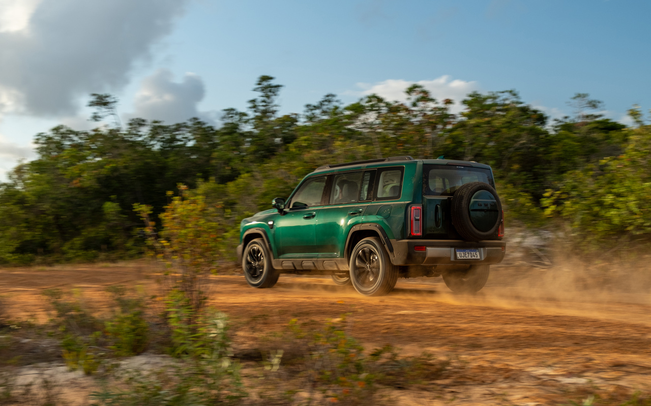 Haval H7 verde visto de três quartos traseiro em estrada de terra