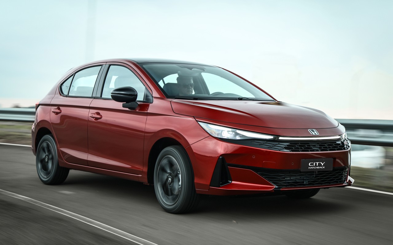 Honda City Hatchback RS 2027 vermelho em movimento, visto de frente e de lado