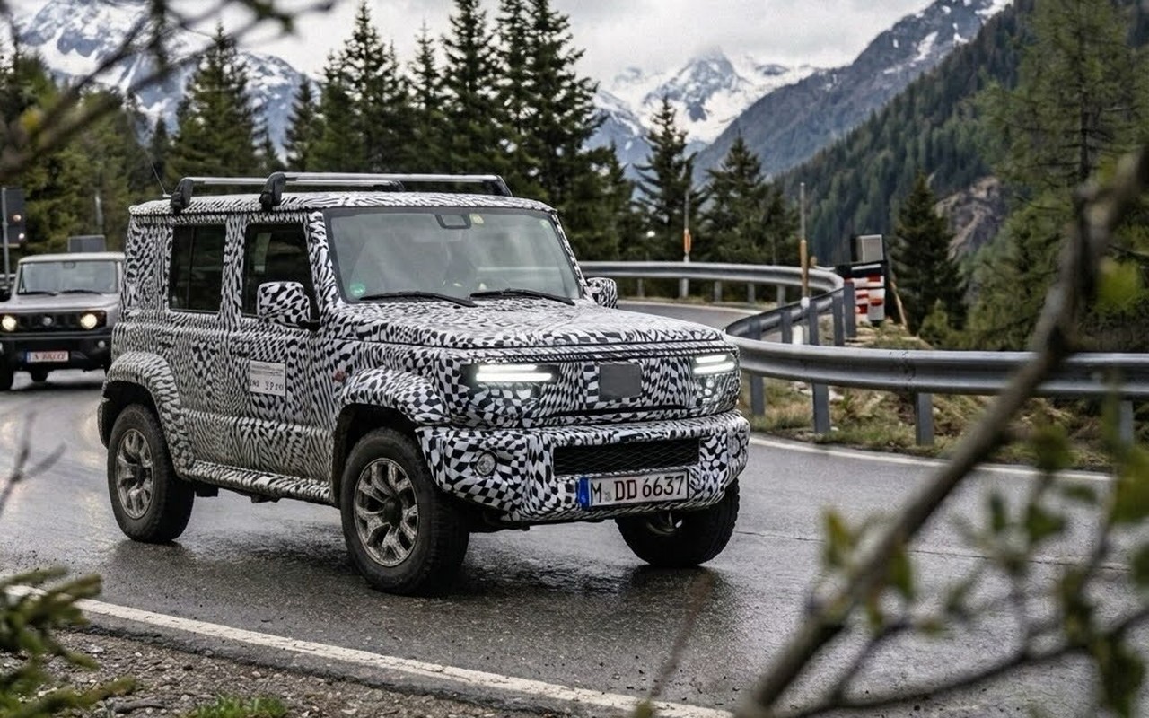 Veículo camuflado com aparência de Suzuki Jimny visto em três quartos dianteiros numa estrada de montanha