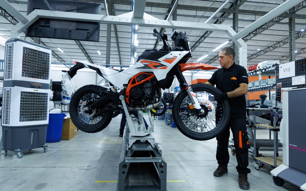 Funcionário trabalha em uma KTM 390 Adventure R elevada na linha de montagem de Manaus