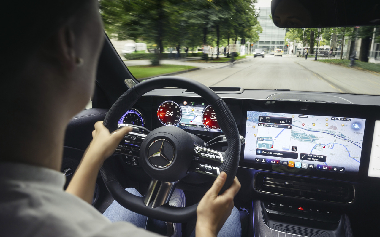 Motorista ao volante de Mercedes-Benz com sistema de assistência e navegação no painel