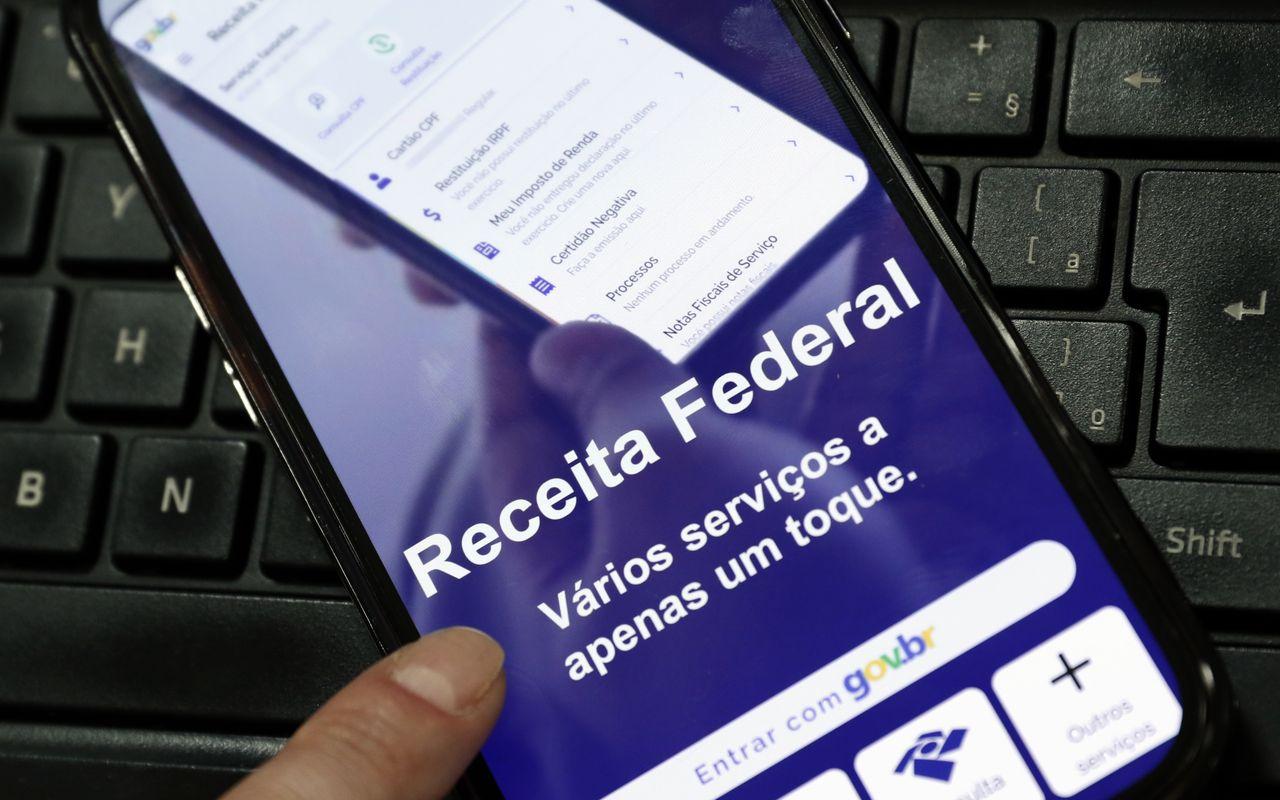 Celular exibe os serviços digitais da Receita Federal sobre um teclado