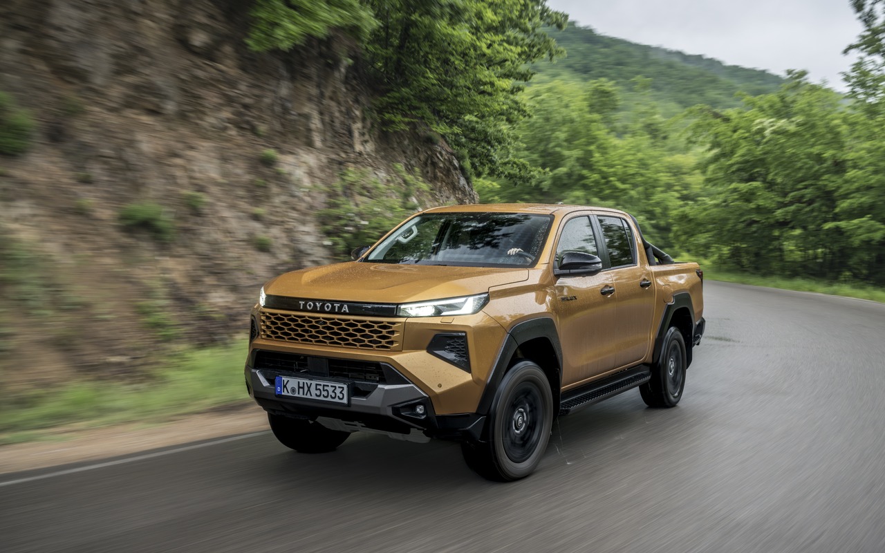 Toyota Hilux de nona geração, dourada, vista de três quartos dianteiro em uma estrada